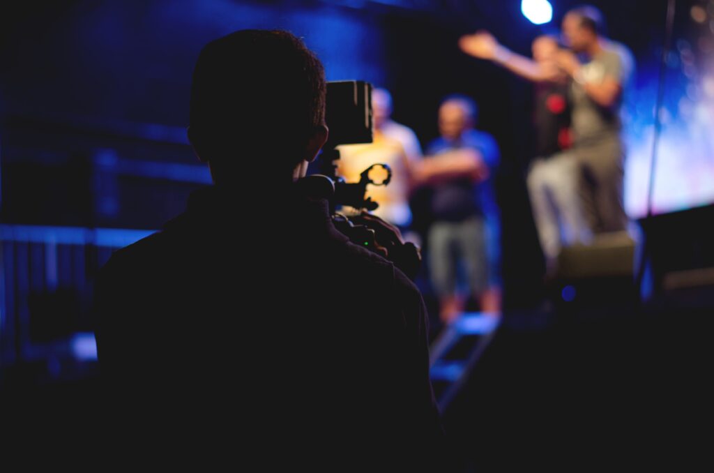 Man shooting a video with people on a stage
