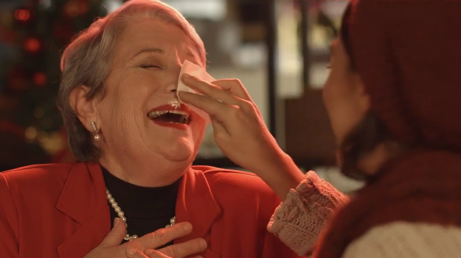 Grandmother wiping coffee foam off her face and laughing
