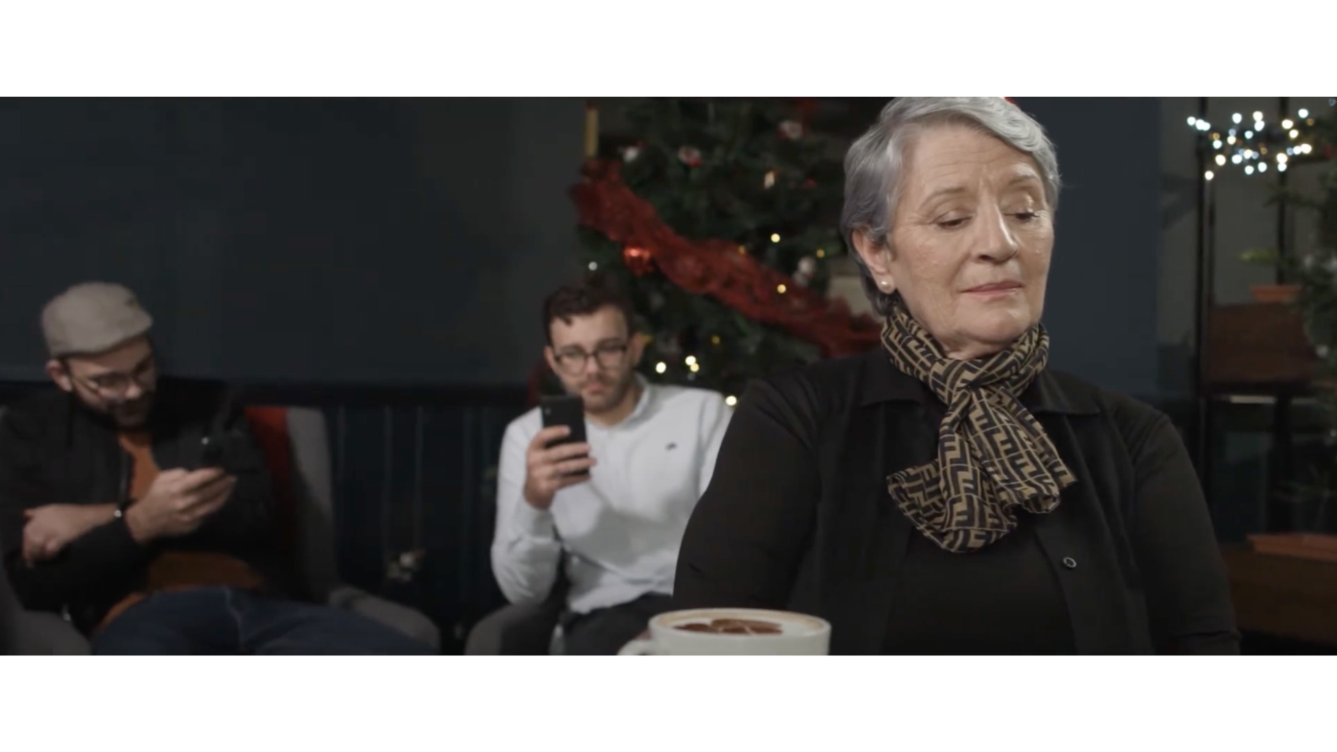 grandmother looking disappointed and in the background there are 2 men on their phone
