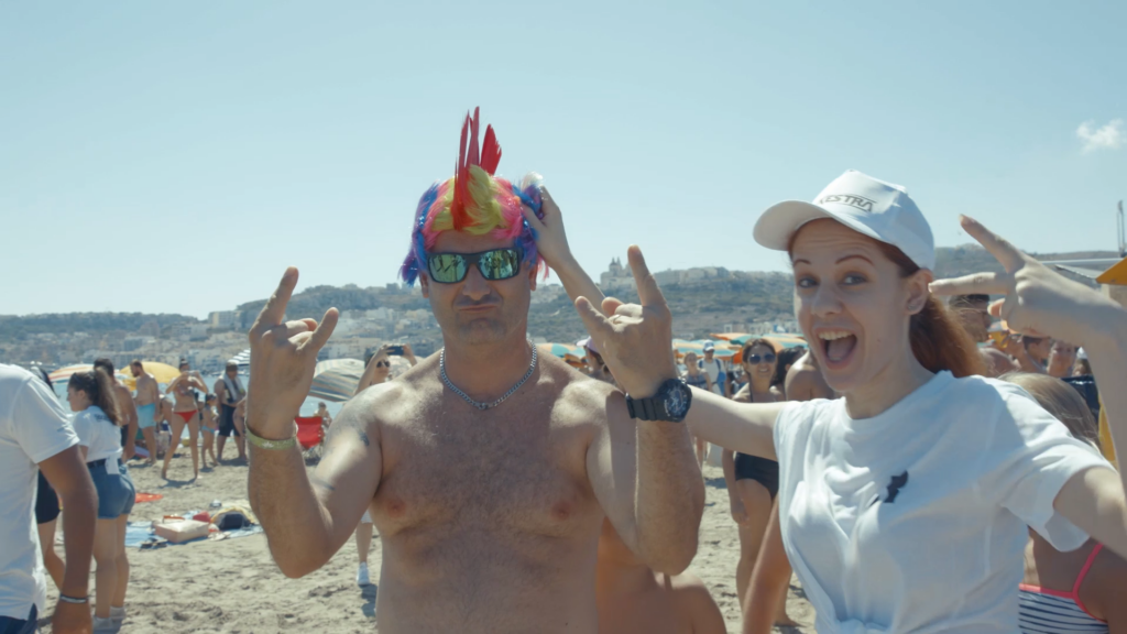 A man and a woman posing with peace signs. The man has a colourful punk wig